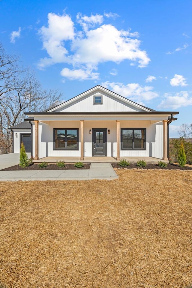 modern farmhouse style home with a porch, a front lawn, driveway, and a garage