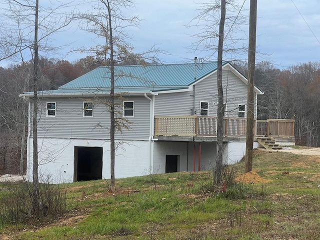 rear view of property featuring metal roof and a wooden deck