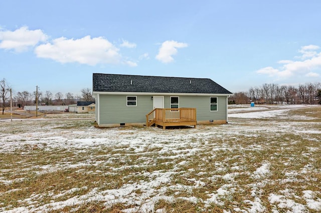 snow covered property with a deck, crawl space, and roof with shingles