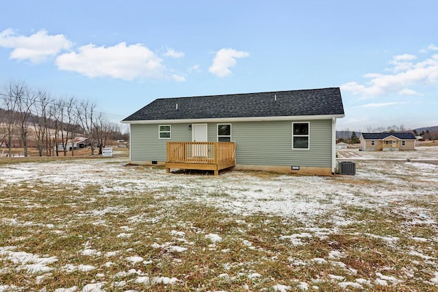 snow covered back of property with a shingled roof, crawl space, a wooden deck, and central AC unit