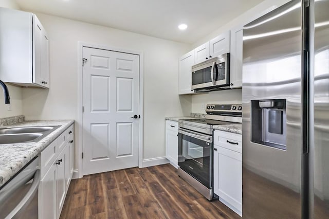 kitchen featuring light stone counters, appliances with stainless steel finishes, dark wood-type flooring, white cabinetry, and a sink