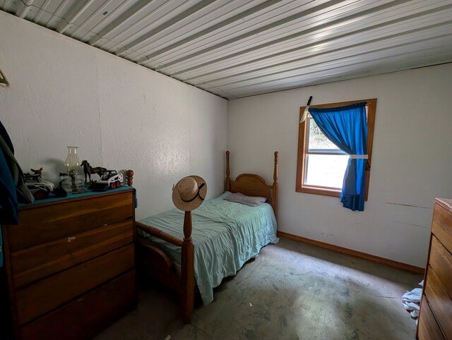 bedroom featuring baseboards and unfinished concrete floors