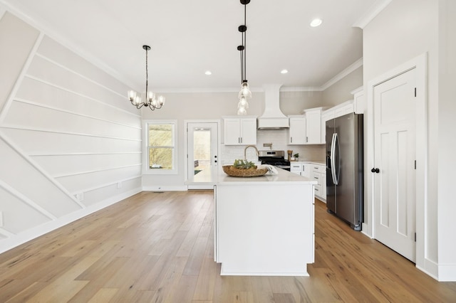 kitchen with light wood-style flooring, ornamental molding, light countertops, custom range hood, and appliances with stainless steel finishes