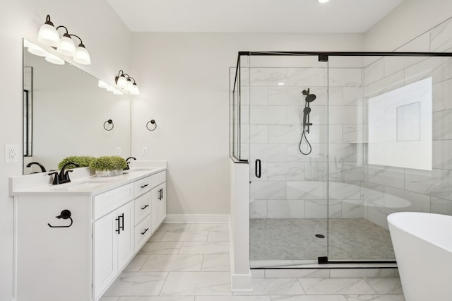 bathroom with double vanity, marble finish floor, a freestanding tub, and a sink