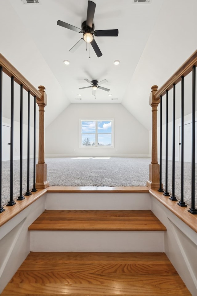 stairs with visible vents, lofted ceiling, and a ceiling fan