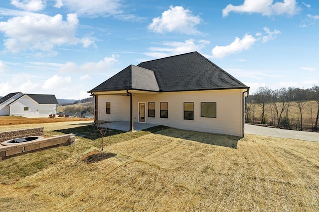 back of house with a patio, a lawn, and roof with shingles