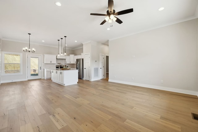 unfurnished living room with ornamental molding, ceiling fan with notable chandelier, light wood-type flooring, and baseboards