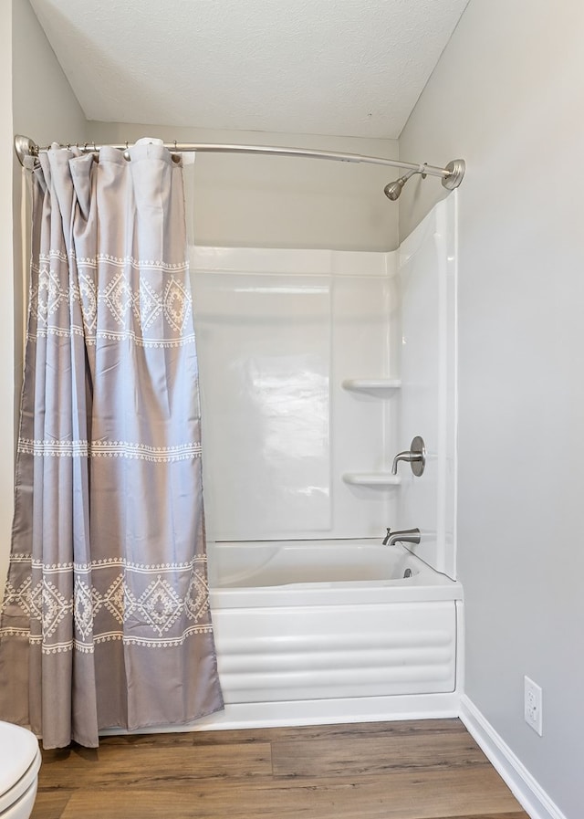 bathroom with wood finished floors, shower / bath combo with shower curtain, toilet, and baseboards