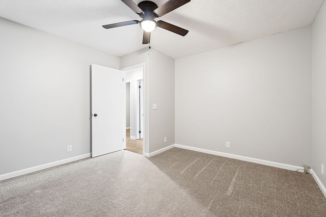 carpeted empty room featuring a textured ceiling, a ceiling fan, and baseboards