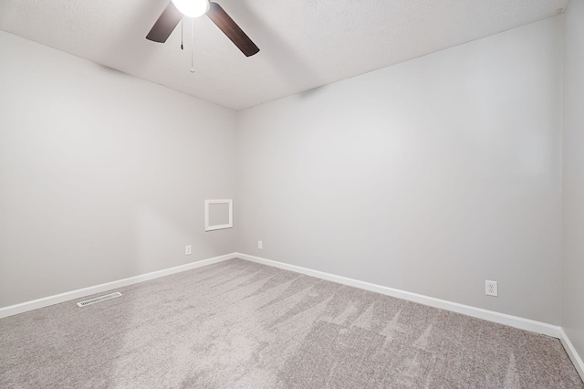 carpeted empty room featuring a textured ceiling, a ceiling fan, visible vents, and baseboards