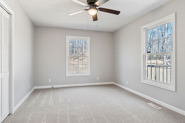 interior space featuring carpet floors, visible vents, a textured ceiling, and multiple windows