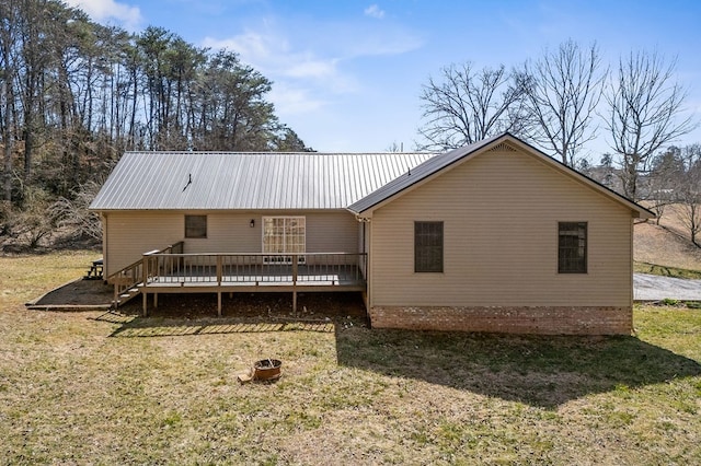 rear view of house featuring metal roof, a deck, and a lawn