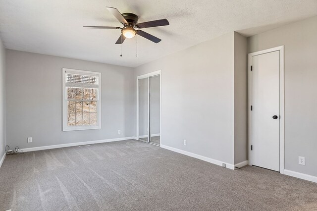 unfurnished bedroom with carpet floors, ceiling fan, a textured ceiling, and baseboards