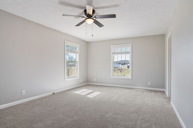 carpeted spare room with ceiling fan, a textured ceiling, and baseboards