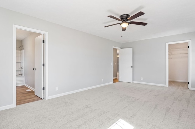 unfurnished bedroom with ceiling fan, baseboards, a closet, carpet, and a walk in closet