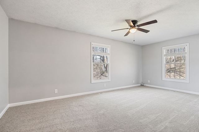 carpeted spare room featuring ceiling fan, baseboards, and a textured ceiling