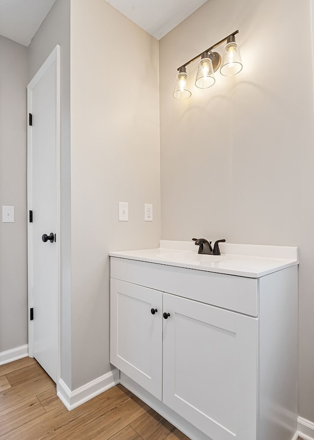 bathroom featuring baseboards, wood finished floors, and vanity