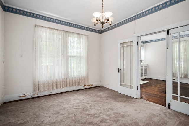 carpeted empty room with an inviting chandelier