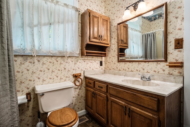 bathroom with vanity, toilet, and wallpapered walls