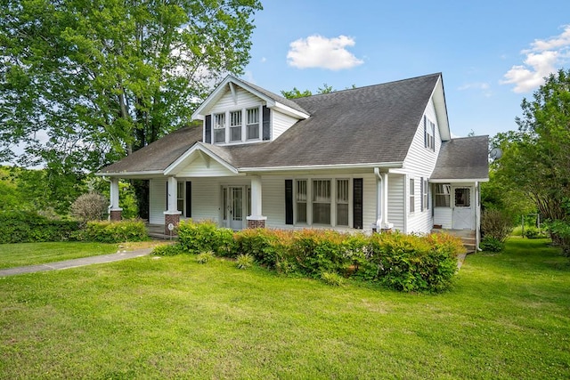 view of front of home with covered porch, a front lawn, and roof with shingles