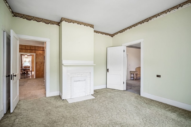 empty room featuring carpet floors, wood walls, and baseboards