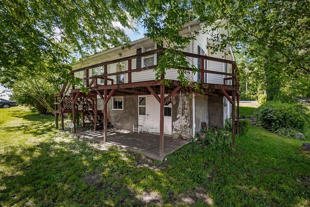 rear view of property featuring a yard, stairway, and a wooden deck