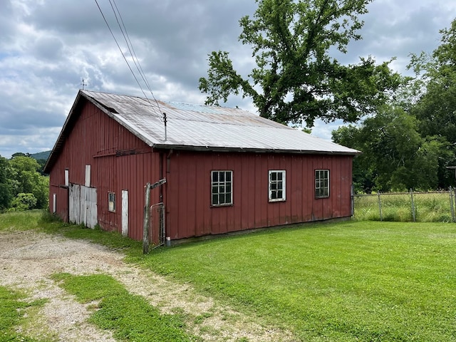 view of outdoor structure featuring an outbuilding, fence, and driveway