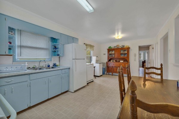 kitchen featuring light floors, open shelves, light countertops, a sink, and white appliances