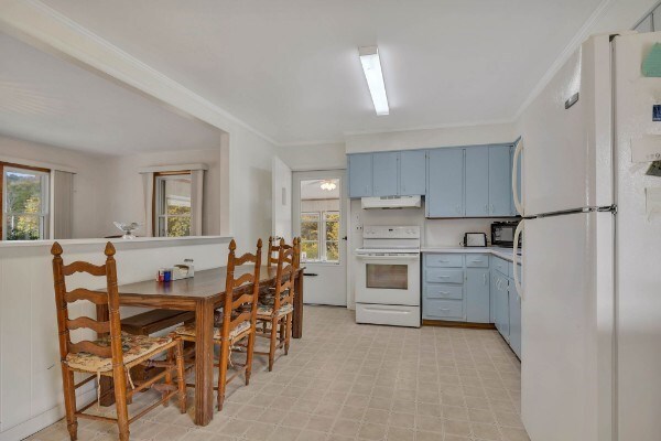 kitchen with blue cabinets, under cabinet range hood, white appliances, light countertops, and crown molding