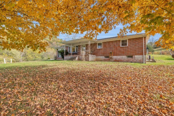 view of front facade with a porch, brick siding, and a front lawn