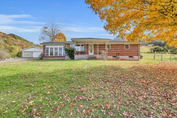 ranch-style home featuring a garage, a front yard, brick siding, and an outdoor structure