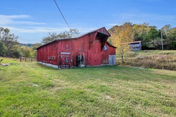 view of barn with a yard, a rural view, and fence