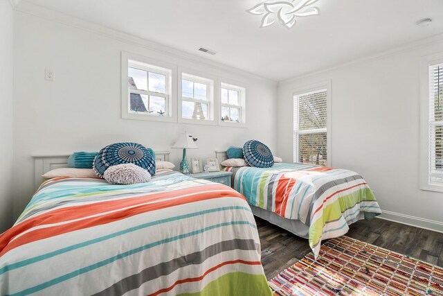 bedroom featuring dark wood-style floors, multiple windows, visible vents, and crown molding