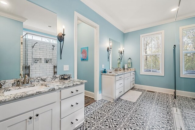 bathroom with crown molding, two vanities, a stall shower, a sink, and baseboards