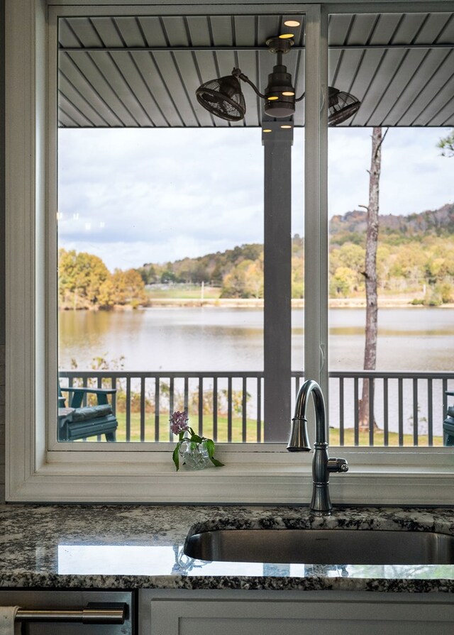 exterior space featuring a water view, stone counters, a sink, and dishwasher