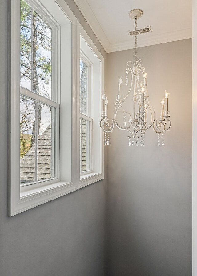 details featuring ornamental molding, visible vents, and a notable chandelier