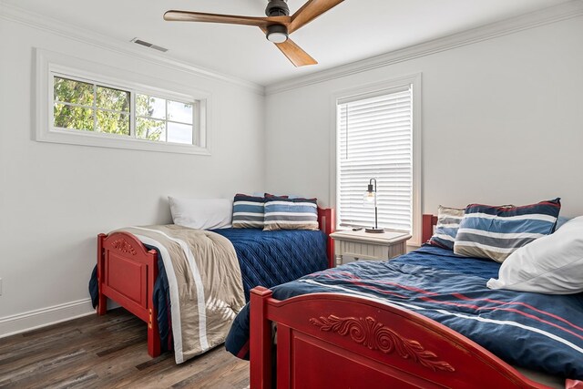 bedroom featuring ceiling fan, visible vents, baseboards, dark wood finished floors, and crown molding