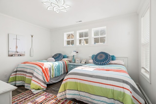 bedroom with multiple windows, wood finished floors, visible vents, and crown molding