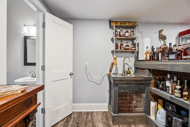 bar with a sink, baseboards, dark wood finished floors, and indoor wet bar