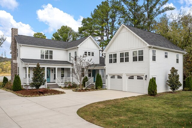 modern inspired farmhouse with an attached garage, covered porch, a front lawn, board and batten siding, and a chimney