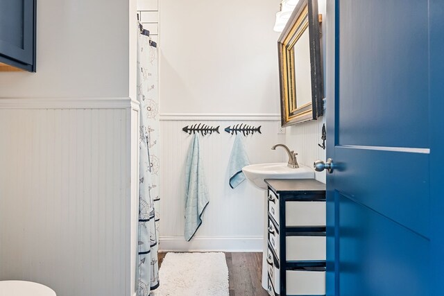 full bath with a wainscoted wall, wood finished floors, and vanity