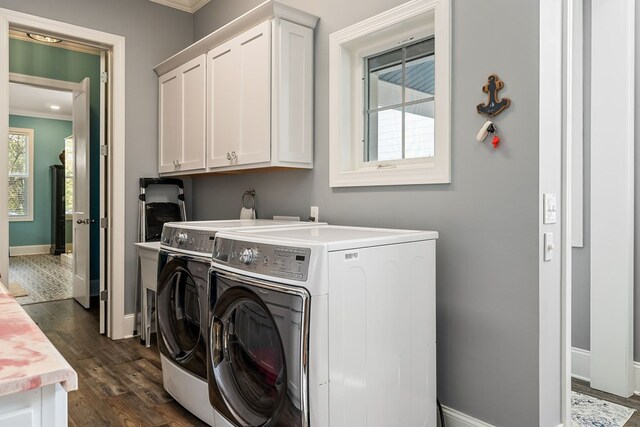 laundry room featuring washing machine and dryer, baseboards, cabinet space, dark wood-style floors, and crown molding