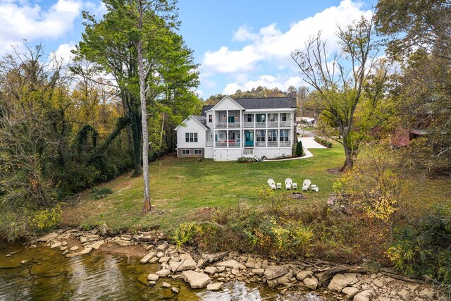 back of property with a water view, a balcony, a chimney, and a yard