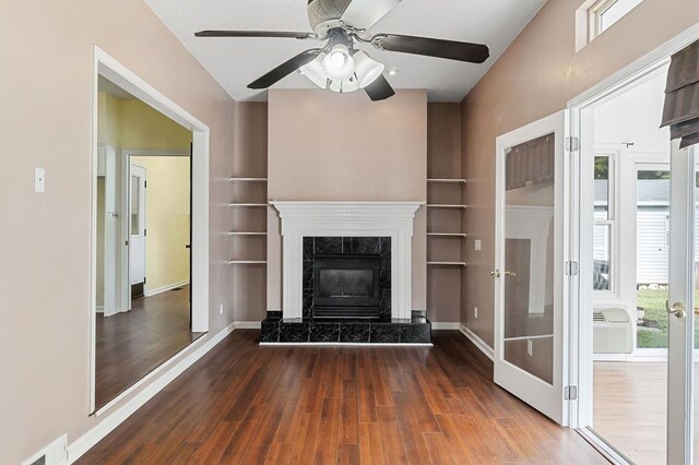 unfurnished living room featuring dark wood-style flooring, a high end fireplace, visible vents, and a healthy amount of sunlight