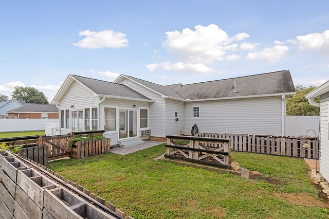 rear view of house featuring entry steps, a yard, and a fenced backyard