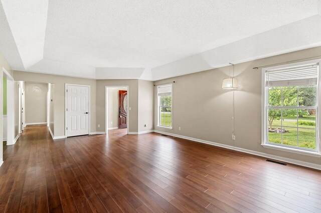 unfurnished room with dark wood-style floors, visible vents, a textured ceiling, and baseboards