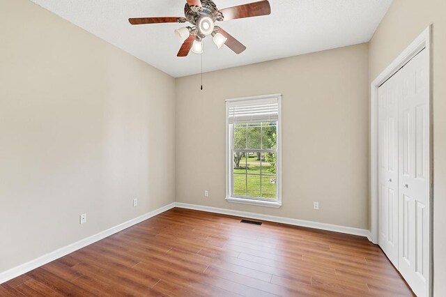 unfurnished bedroom featuring a closet, wood finished floors, visible vents, and baseboards