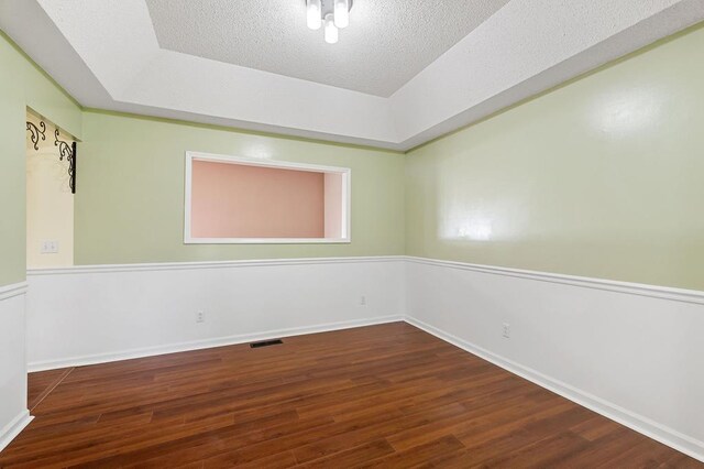 unfurnished room with dark wood-style floors, visible vents, a textured ceiling, and baseboards