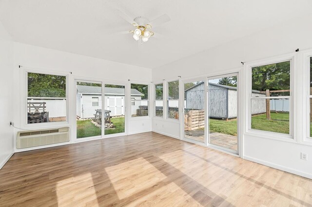 unfurnished sunroom with a wall unit AC and a ceiling fan