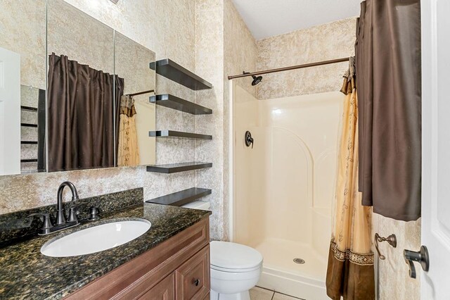 full bathroom featuring toilet, tile patterned floors, a shower stall, and vanity